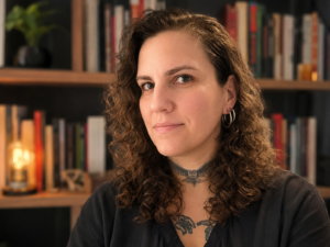 Escritora Camila Mossi posando em frente a uma estante de livros