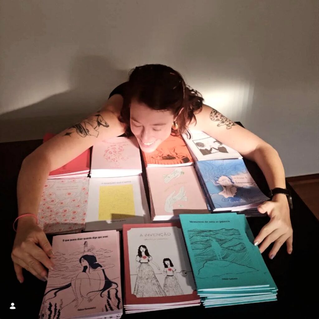 Editora Amanda Damásio posa junto ao livro Lembrança de Esquecer, da escritora Camila Mossi, e das demais obras lançados pela editora Outra.